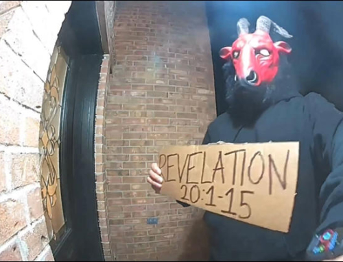 Unknown man wearing satanic mask holding sign with apocalyptic Bible verse